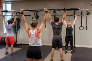 group fitness class doing a workout with a barbell with no weights