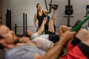 fitness class using exercise bands while coach watches